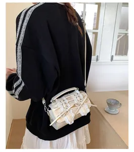 Detalle del bolso cilíndrico de encaje crema con lazo y diseño elegante juvenil
