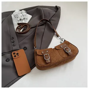 Primer plano del bolso de ante marrón con bolsillos dobles y funda de móvil a juego