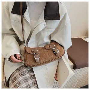 Detalle de bolso bandolera de ante marrón vintage con dos bolsillos de hebilla y tachuelas
