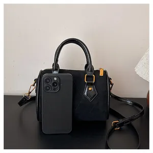 Detalle del mini bolso negro con textura de ante mate y cremallera metálica dorada