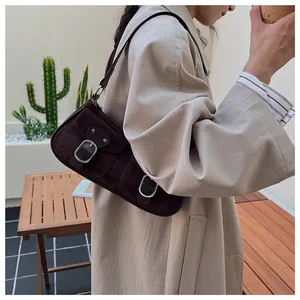 Detalle de bolso de hombro en ante marrón oscuro con hebillas metálicas plateadas