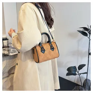 Detalle de un bolso Boston acolchado marrón con asas negras sobre una modelo