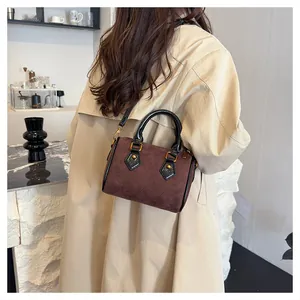Detalle del bolso Boston de ante marrón acolchado con herrajes dorados y correa cruzada