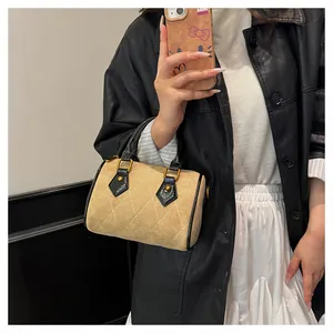 Detalle del bolso tipo almohada de ante caqui con costuras de diamante y asas de cuero negro