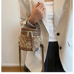 Detalle de bolso tipo cubo en contraste con tejido de felpa beige y cuero sintético