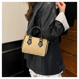 Detalle del bolso acolchado de ante beige con ribete de cuero negro y remaches dorados
