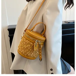 Detalle de bolso cubo amarillo con textura de peluche y correas de cuero en blazer blanco