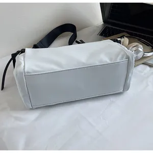 Detalle del bolso bandolera blanco en tela Oxford impermeable con correa ancha negra