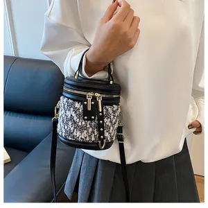 Detalle del bolso de cubo con costuras contrastadas y textura de herrajes metálicos