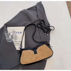 Detalle del bolso vintage de gamuza marrón acolchada con adornos de cuero negro y hebillas