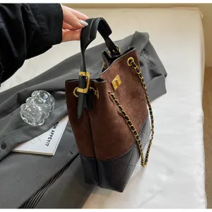 Detalle del bolso de cubo en gamuza marrón y cuero acolchado negro con costuras de rombos