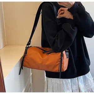 Detalle del bolso bandolera cilíndrico en tejido oxford impermeable naranja vibrante