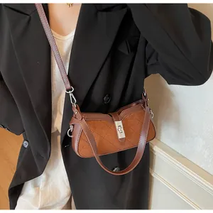Detalle de bolso bandolera vintage con ante acolchado y textura de cuero marrón