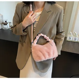 Détail d'un sac à main en fausse fourrure rose avec poignée plissée et bandoulière.