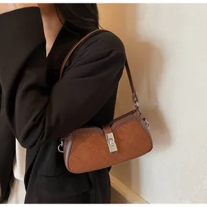 Detalle de bolso bandolera vintage acolchado marrón con cierre giratorio metálico en la modelo
