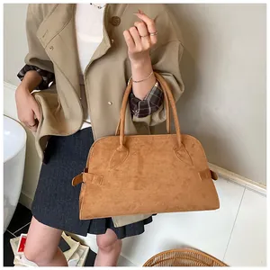 Detalle de bolso tote en cuero mate color camello con hebilla lateral ajustable y asas