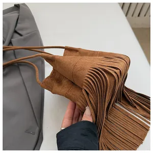 Detalle de bolso saco de ante marrón con flecos largos y correa fina de cordón