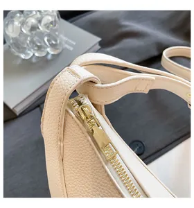 Détail du sac bandoulière crème en cuir grainé avec fermeture éclair dorée et coutures