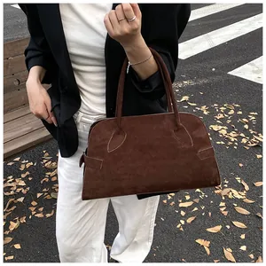 Detalle del bolso de ante marrón oscuro con costuras vintage y textura mate suave