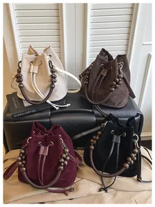 Detalle de bolsos tipo cubo de ante en varios colores con asas de cuentas y textura