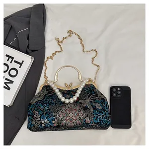 Detailed shot of embroidery shell bag with pearl handle and metal chain for scale