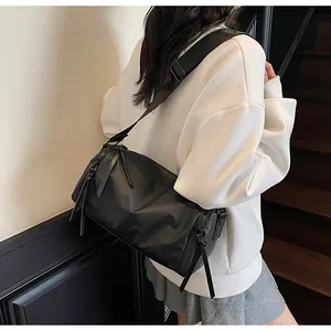 Detalle del bolso bandolera de nailon negro impermeable con borlas de cuero en cremallera