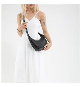 Détail du sac croissant en cuir grainé noir avec logo doré et fermeture éclair élégante