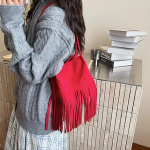 Bolso saco rojo mate con flecos largos mostrado en modelo con ropa de estilo casual