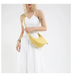 Détail du sac demi-lune jaune avec texture litchi et pliage décoratif sur le côté