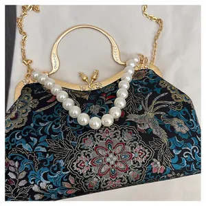 Detail of floral brocade shell bag with pearl handle and golden frame clasp