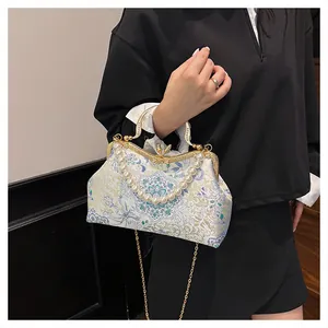 Detail of floral brocade shell bag with large pearl handle and ornate gold clasp