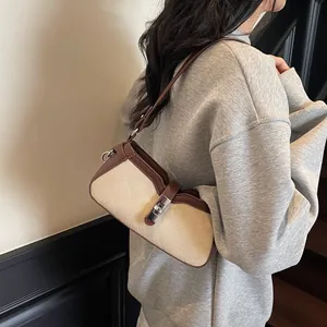 Bolso bandolera vintage acolchado en beige y marrón con hebilla de metal llevado por modelo