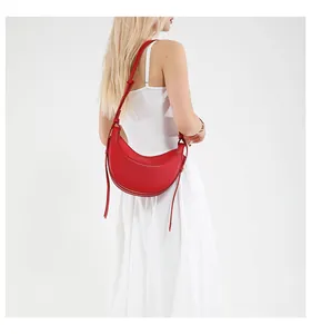 Vue détaillée d'un sac demi-lune rouge texturé porté sur une robe blanche élégante