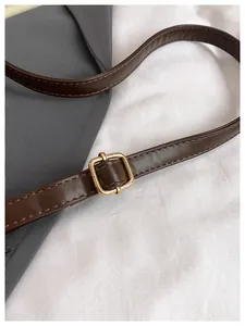 Detalle de correa de cuero sintético marrón oscuro con hebilla dorada y costuras