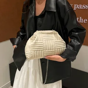 Bolso tipo concha beige tejido con cadena plateada lucido por modelo con chaqueta
