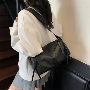 Bolso bandolera cilíndrico negro impermeable con correa ancha ajustable usado por una modelo