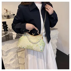 Detail of floral jacquard fabric with pearl handle and golden chain on shell bag