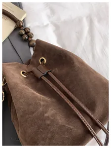 Primer plano de bolso saco de ante marrón vintage con correa de cuentas de madera y cordón
