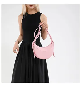 Détail du sac hobo rose à texture litchi et lettrage doré sur une robe noire élégante