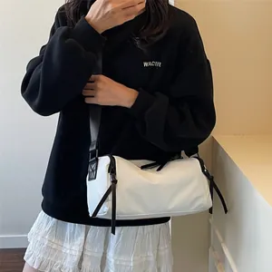 Bolso cilíndrico blanco impermeable con ribete negro y correa ajustable en el modelo