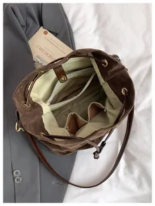 Detalle interior del bolso cubo de ante marrón con forro verde y múltiples bolsillos