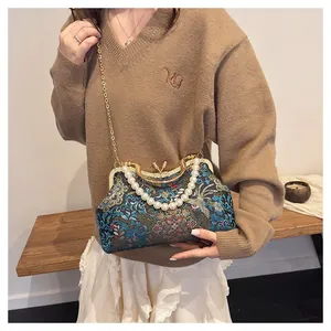 Detail of embroidered floral shell bag with pearl handle and golden chain on model