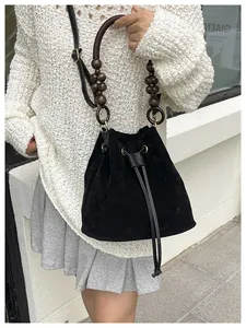 Detalle de bolso saco de ante negro con asa de cuentas de madera vintage y cordón de cierre