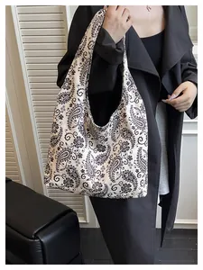 Detail of canvas tote bag showing black paisley patterns on a cream-colored fabric