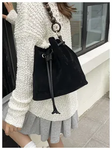 Detalle de bolso saco de ante negro con correa de cuentas de madera vintage y cierre cordón