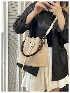 Detalle de bolso saco de ante con asa de cuentas de madera y correa de cuero blanco