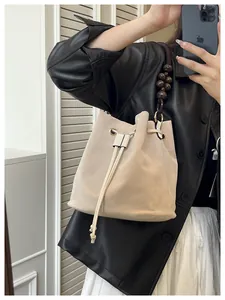 Detalle de bolso bucket de ante beige con correa de cuentas retro y cierre de cordón