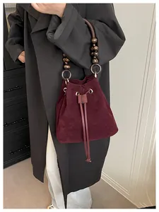 Detalle de bolso cubo de ante burdeos con asa de cuentas de madera vintage y herrajes dorados