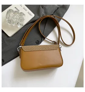 Détail d'un sac bandoulière marron avec texture tressée et boucles en métal argenté