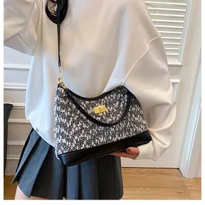 Detalle del bolso de tweed con cierre de giro dorado y ribete de cuero negro en modelo